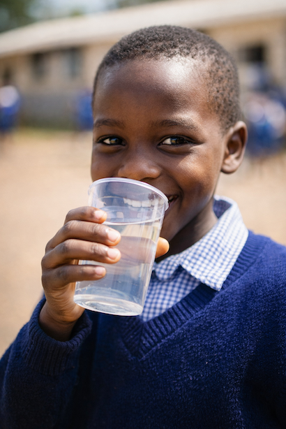 A young Kenyan child drinking clean water from a glass, the next generation MiMaji Foundation's school WASH programme works to protect